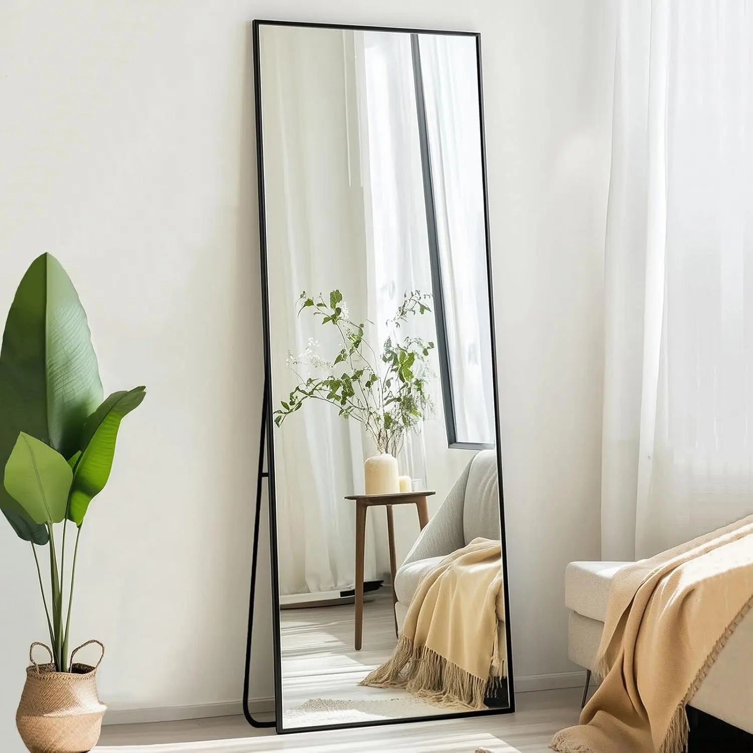 Arched full length mirror with stand in bedroom with plant and armchair